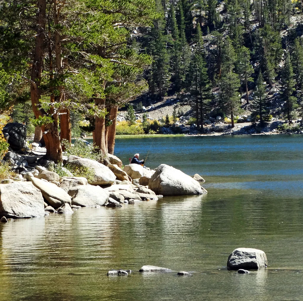 An angler fishes from the boulder-lined shore of Rock Creek Lake.
